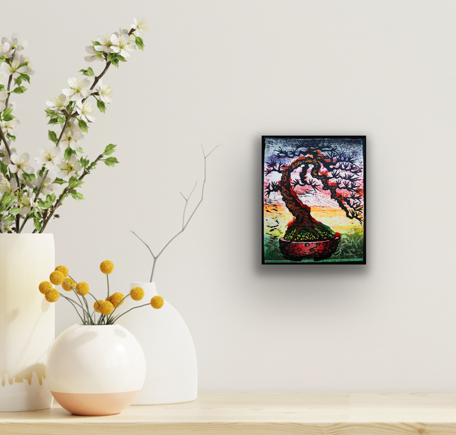 Bowing Tree Monoprint #2 displayed in a black frame on a neutral wall above a wooden table with decorative flower arrangements, illustrating the artwork in a contemporary interior.